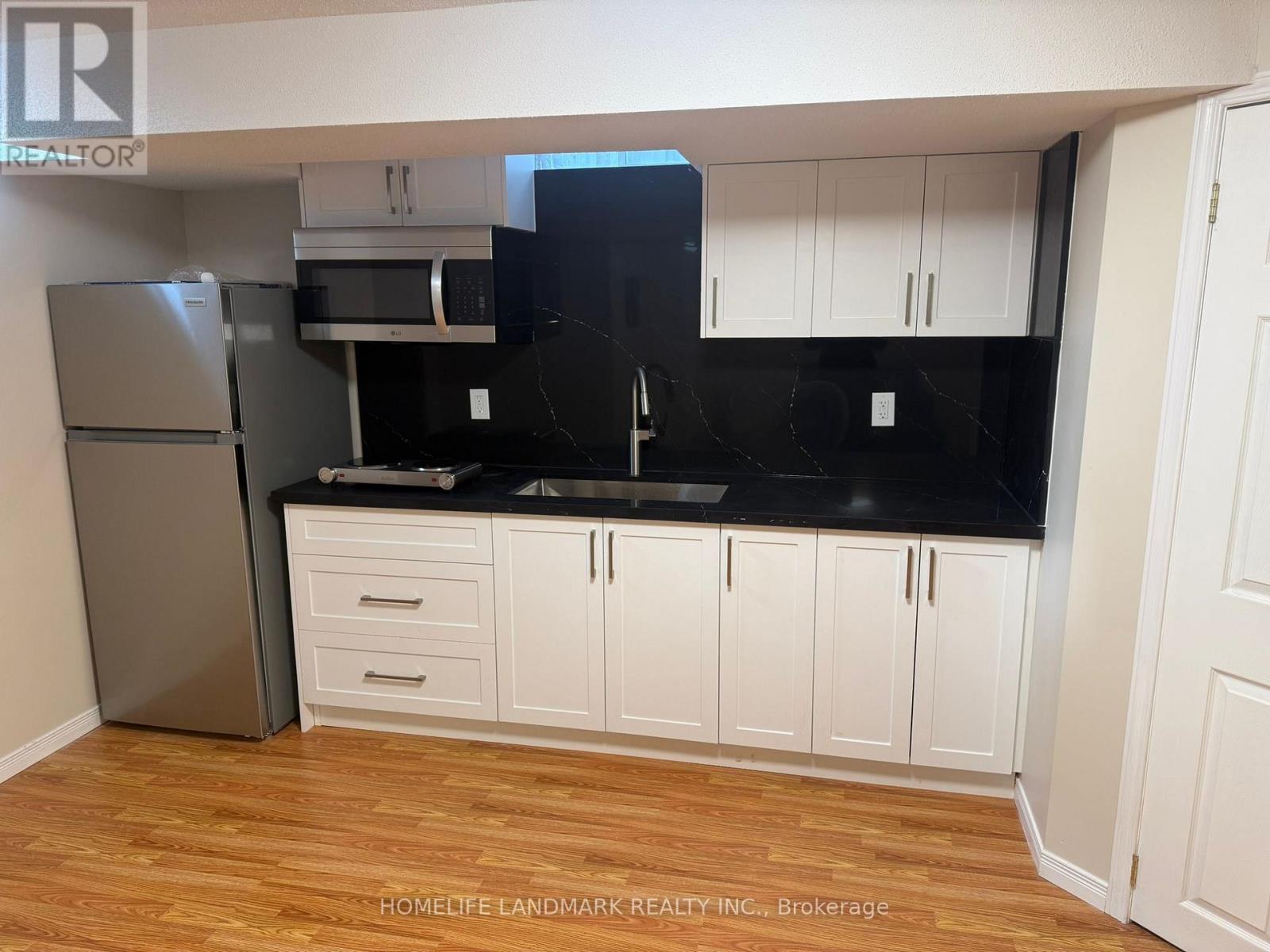 A kitchen with white cabinets and a black countertop.