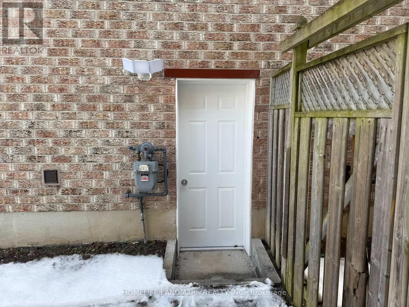 A white door is on the left side of a brick wall.