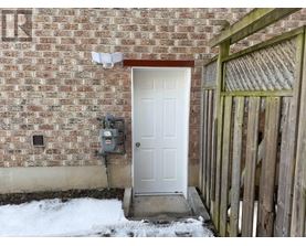 A white door is on the left side of a brick wall.