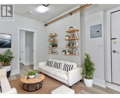 A living room with a white couch, a coffee table, and a plant.
