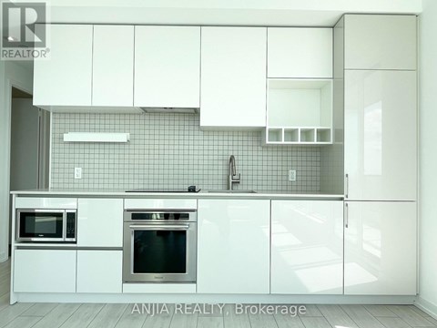 A modern kitchen with white cabinets and appliances.