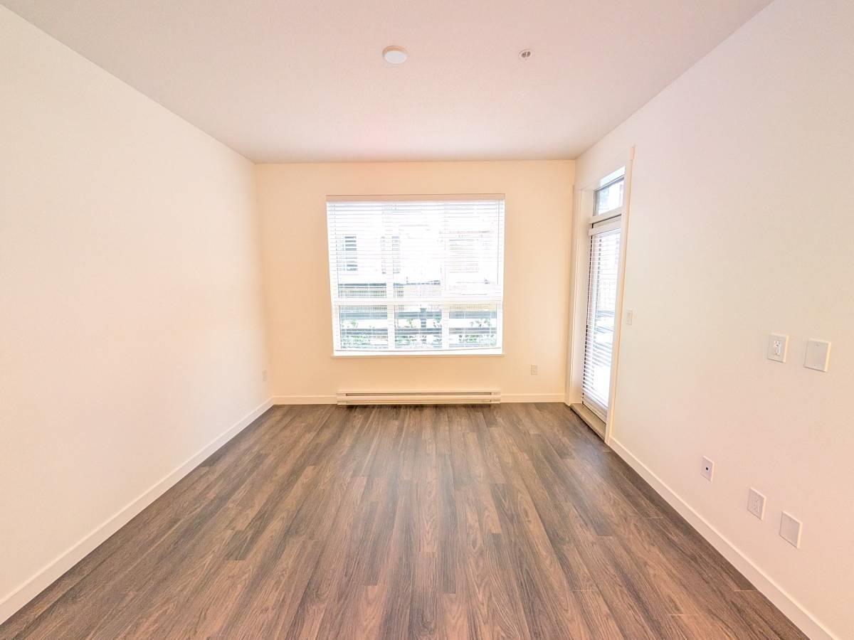 A room with wooden flooring and a window showing a view of a building.