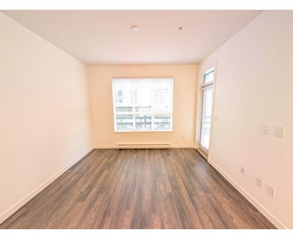 A room with wooden flooring and a window showing a view of a building.