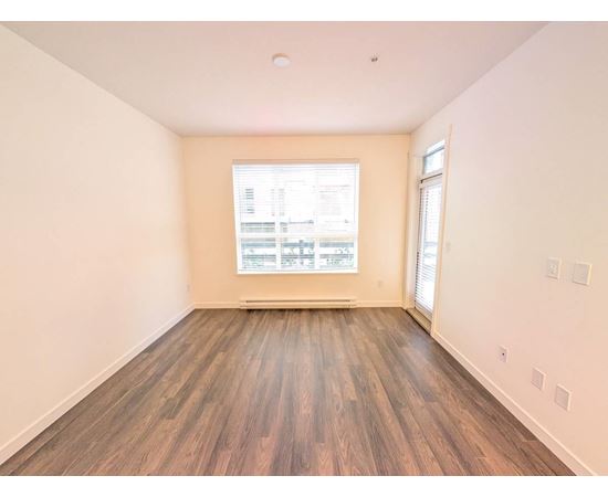 A room with wooden flooring and a window showing a view of a building.