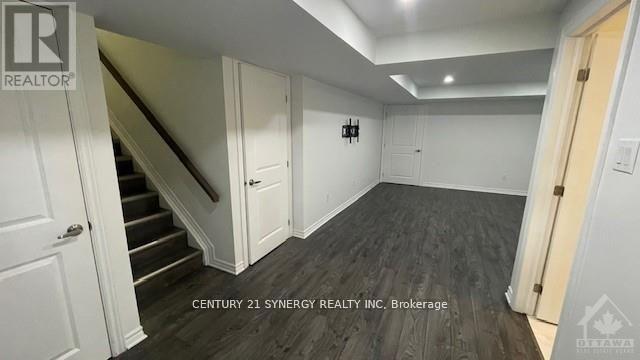 A spacious room with a staircase and a door on the right side.