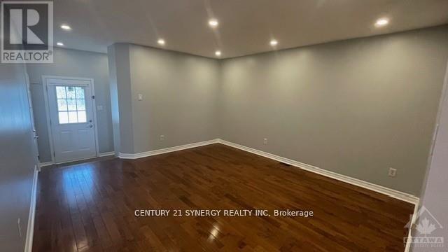 A room with wooden flooring and a doorway leading to another room.