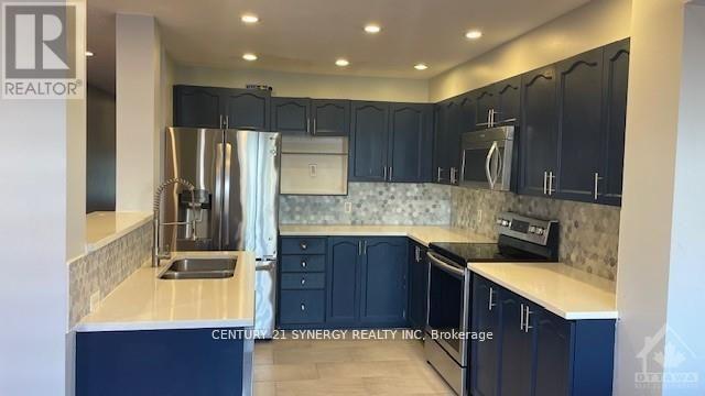 A kitchen with dark blue cabinets and a stainless steel refrigerator.