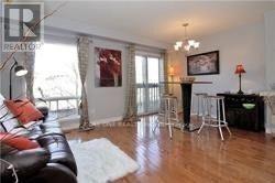 A living room with a black leather couch and a white rug.