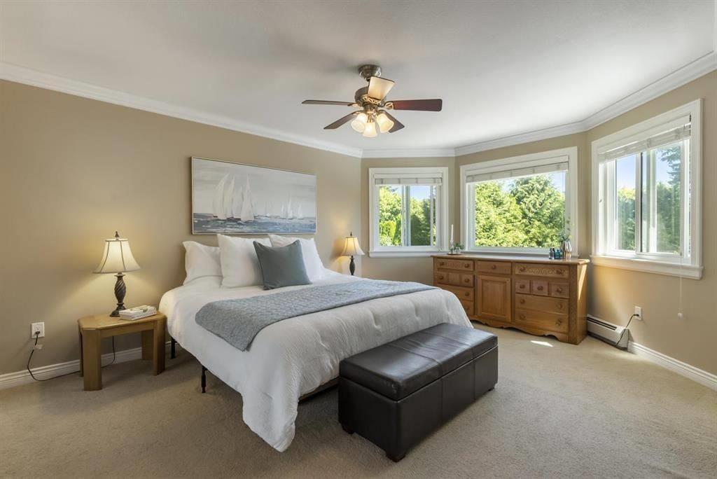 A bedroom with a large bed and a ceiling fan.