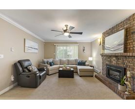 A living room with a fireplace and a ceiling fan.