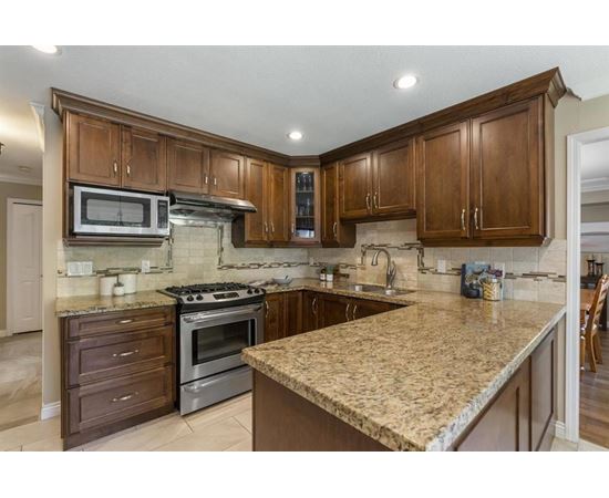 A kitchen with brown cabinets and granite countertops.
