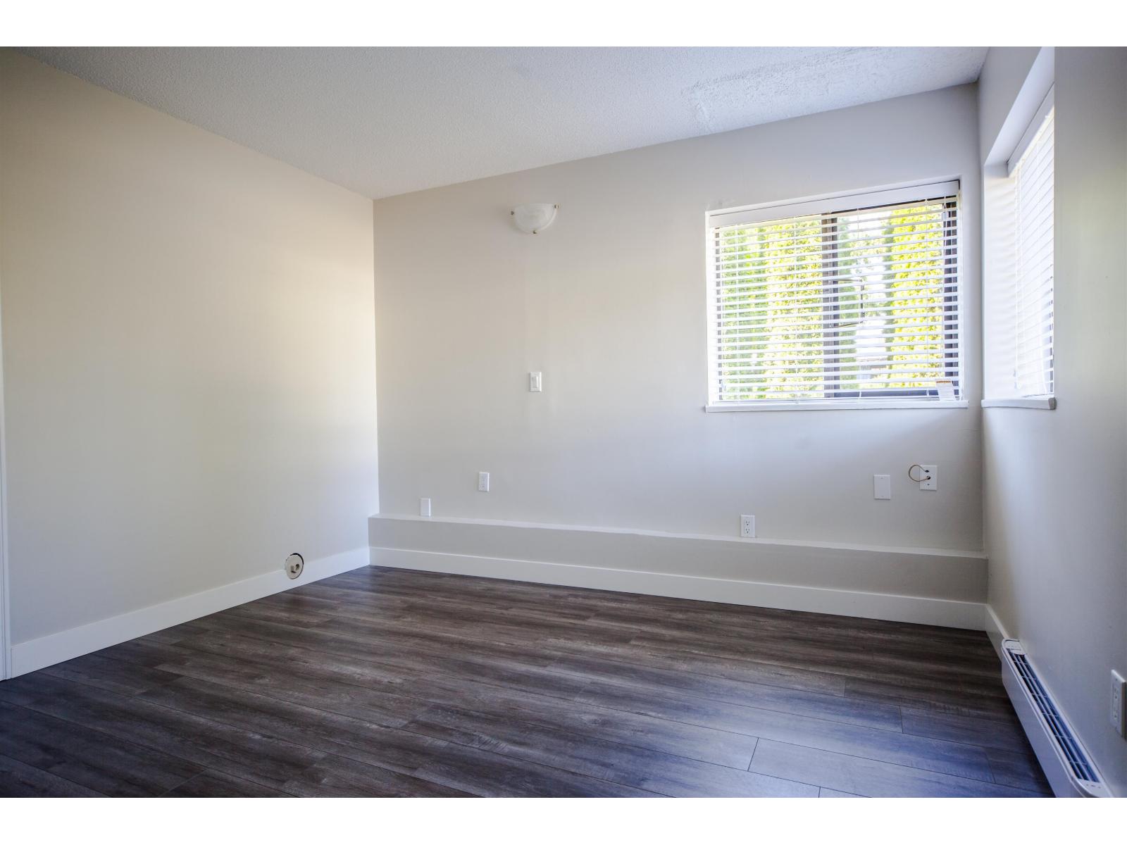 A room with a window and wooden flooring.