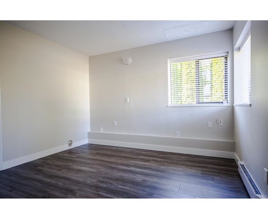 A room with a window and wooden flooring.