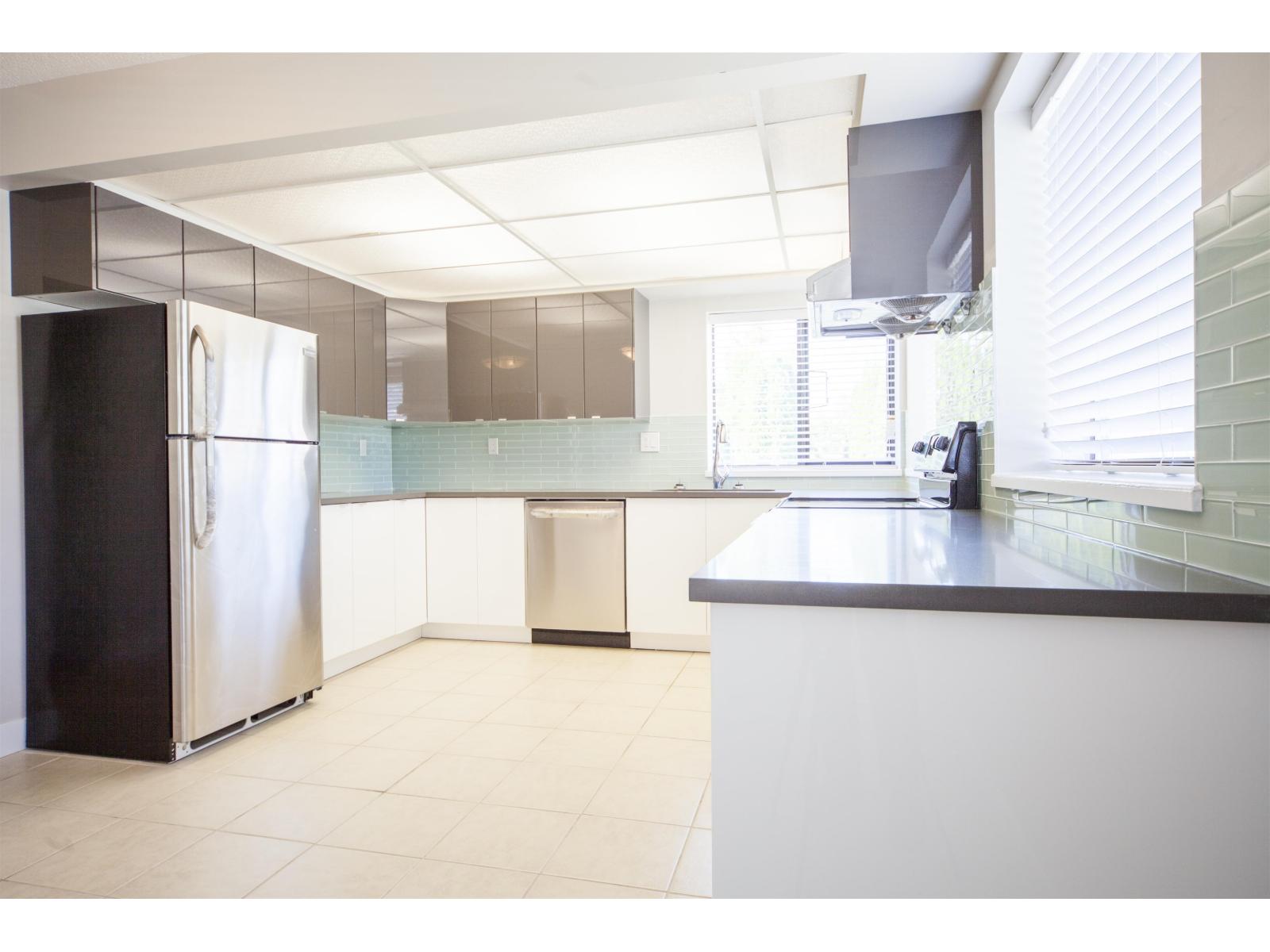 A kitchen with a black refrigerator and white cabinets.