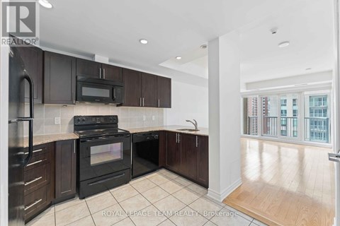 A modern kitchen with dark brown cabinets and a black stove top oven.