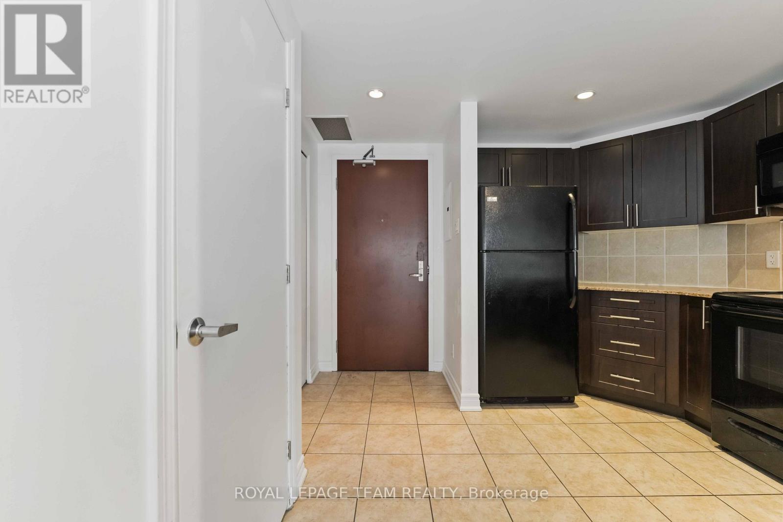 A kitchen with a refrigerator, microwave, and oven.