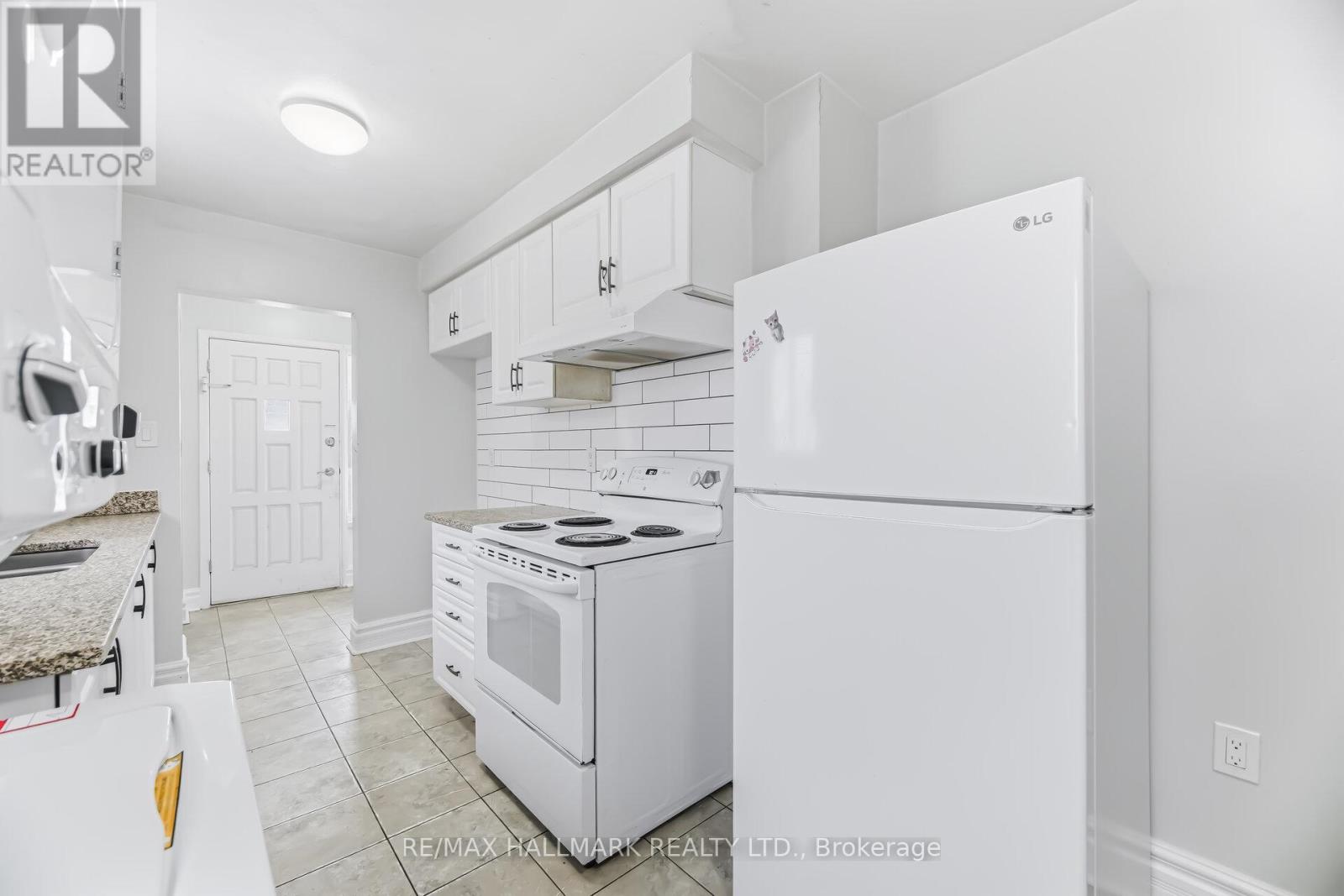 A white kitchen with a stove and refrigerator.