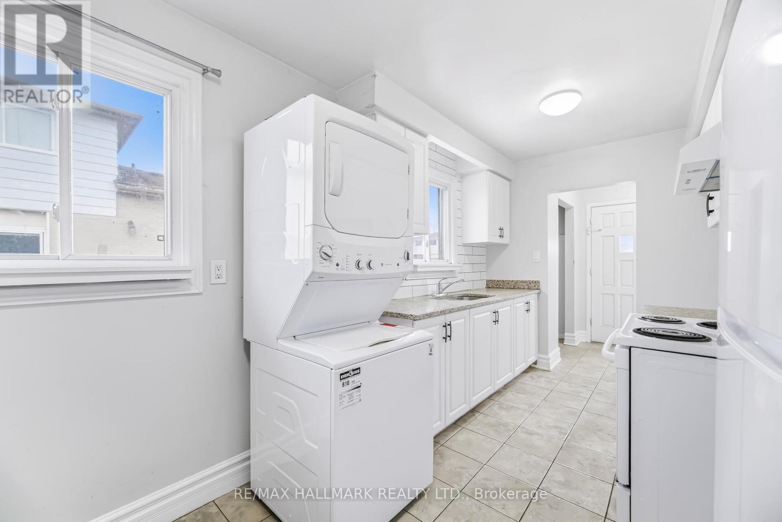A white kitchen with a washing machine in the middle.