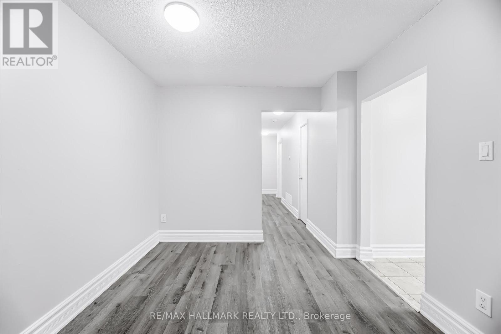 A spacious room with wooden flooring and white walls.