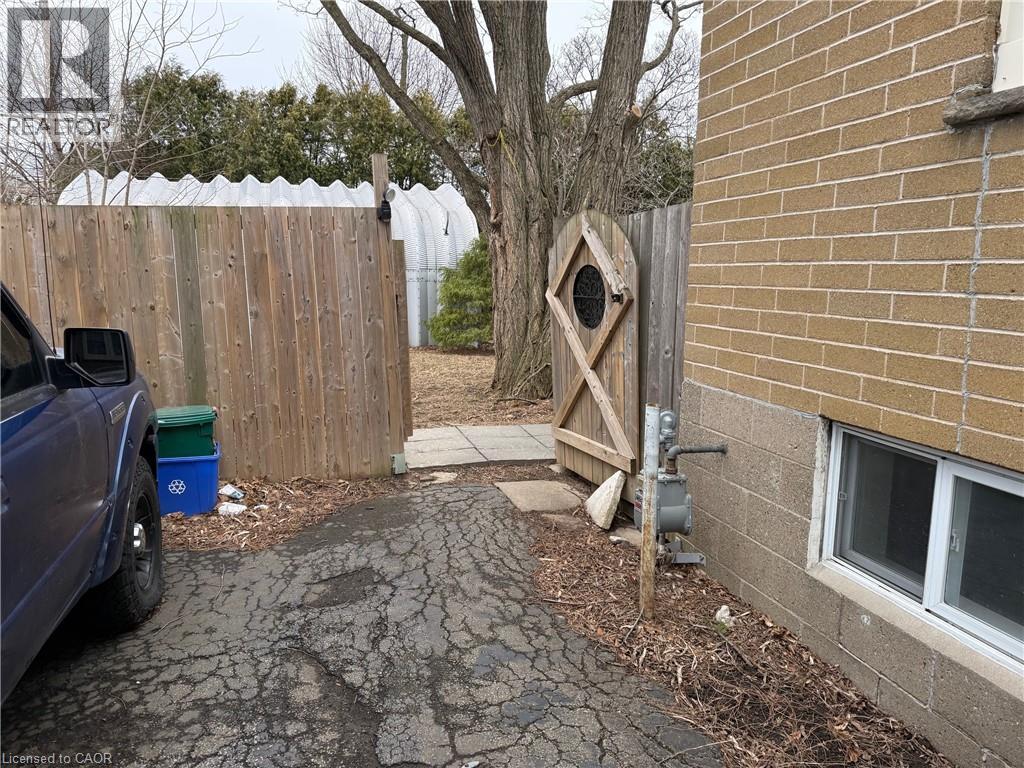 A blue truck is parked in a driveway next to a wooden fence and a tree.