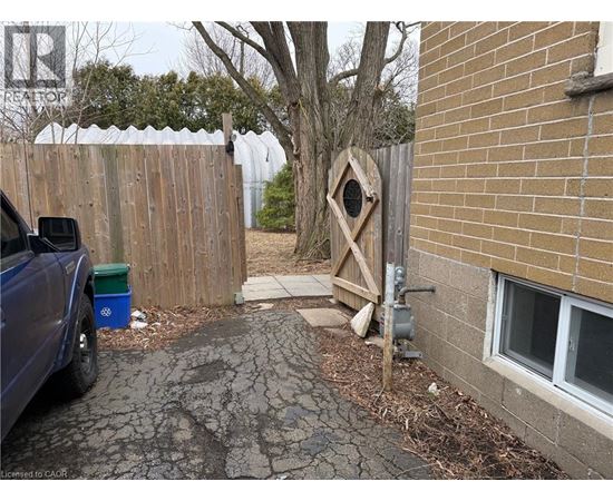 A blue truck is parked in a driveway next to a wooden fence and a tree.