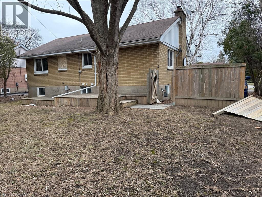 A house with a brown fence and a tree in front.