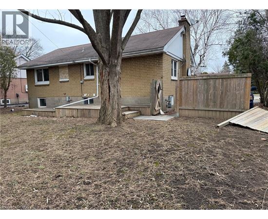 A house with a brown fence and a tree in front.