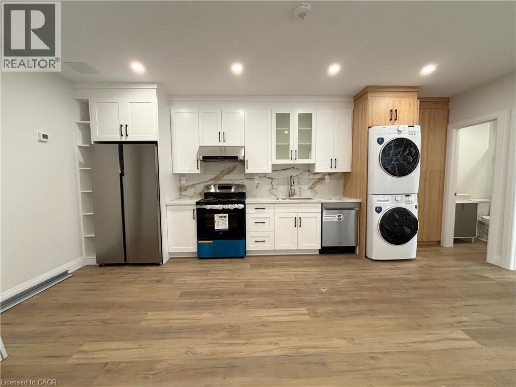 A kitchen with a refrigerator, oven, dishwasher, and washing machine.