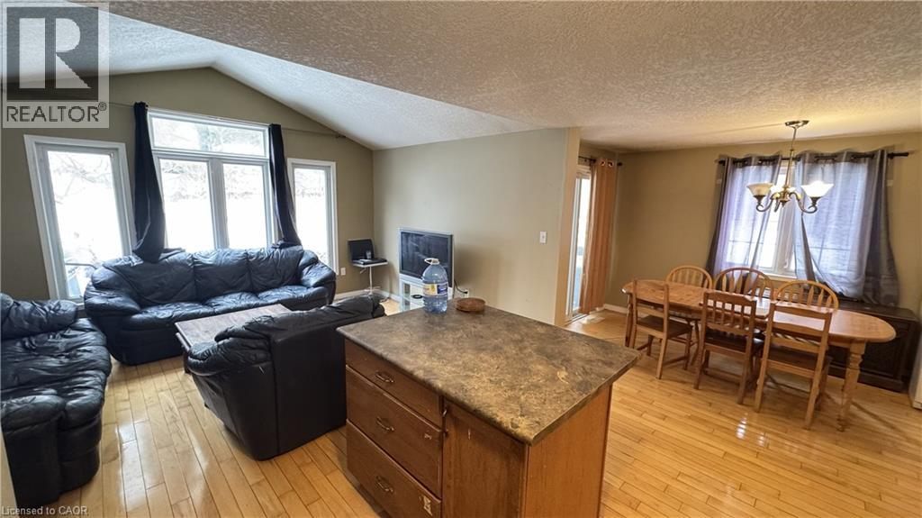 A living room with a black leather couch and a wooden dining table.