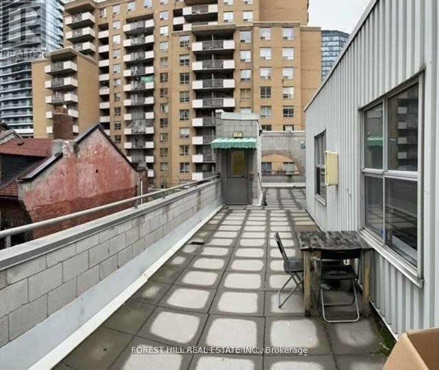 A balcony with a table and chairs overlooks a cityscape.