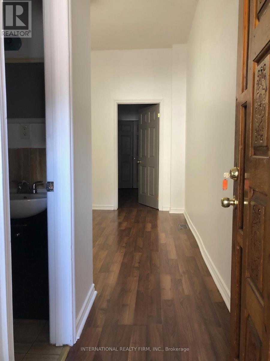 A hallway with a door on the right and a sink in the bathroom on the left.