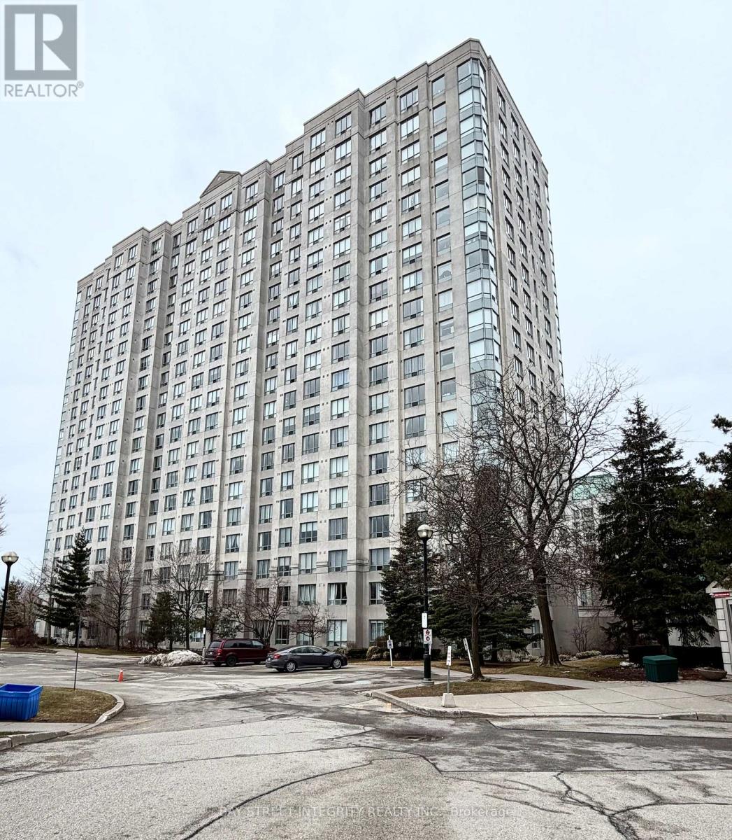 A tall building with many windows is surrounded by a parking lot.