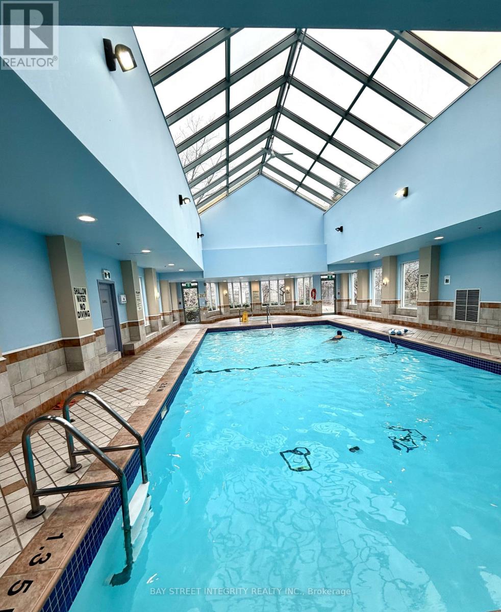 A swimming pool inside a building with a glass ceiling.