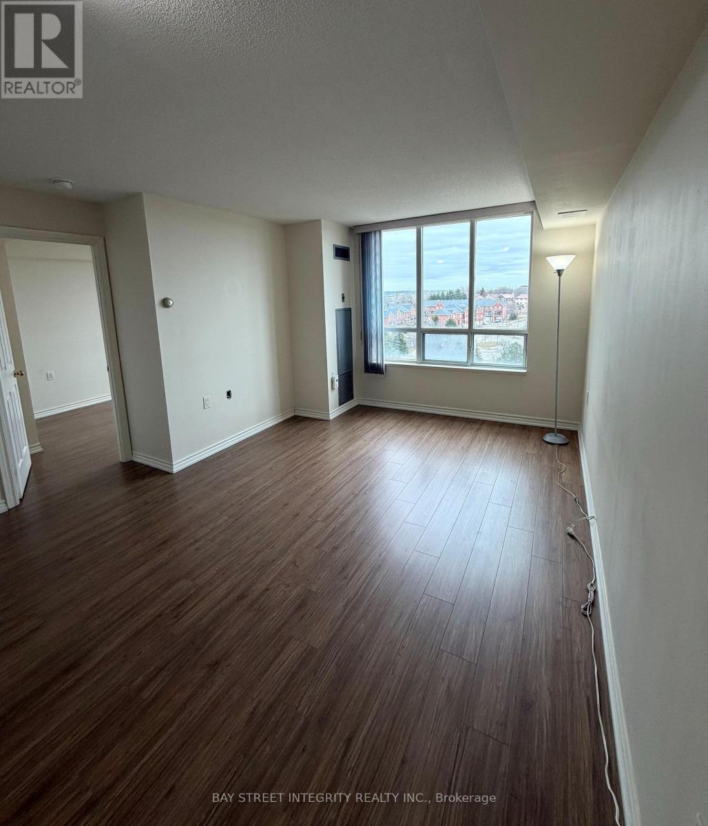 A room with wooden flooring and a window overlooking a cityscape.