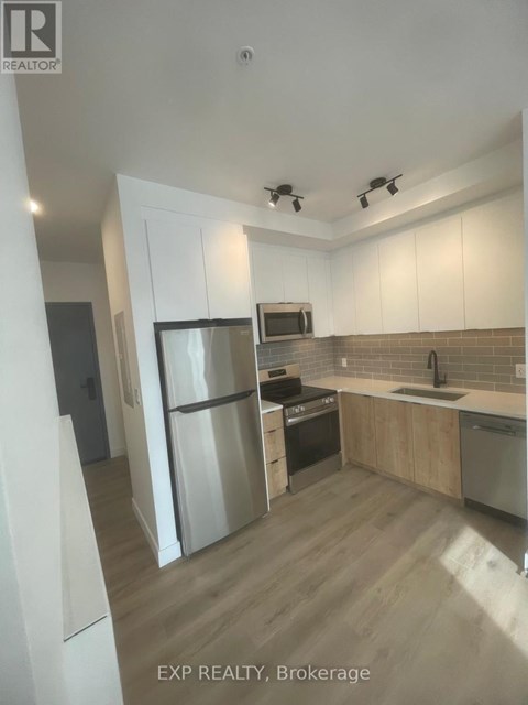 A kitchen with white cabinets and a refrigerator.