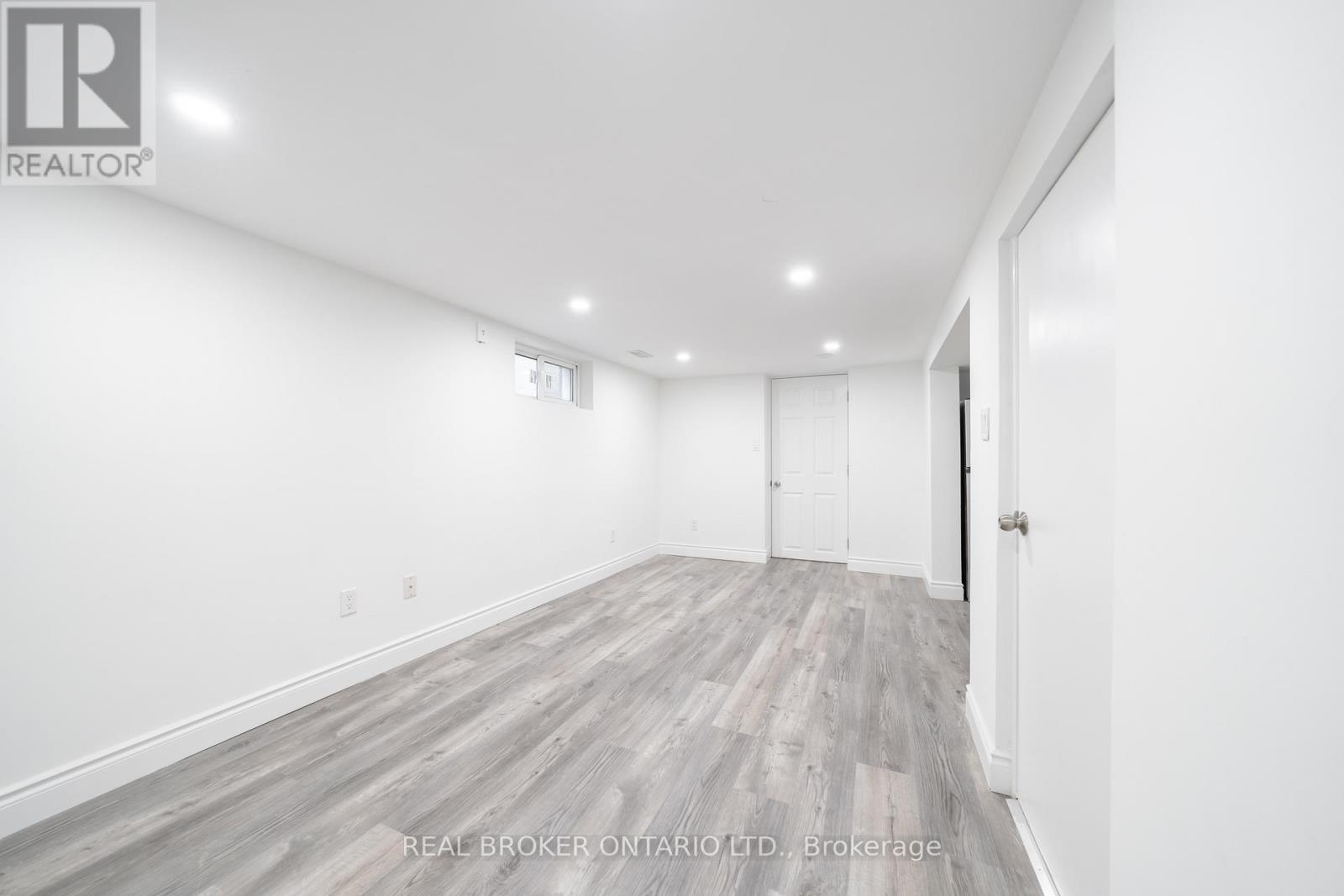 A spacious room with wooden flooring and white walls.