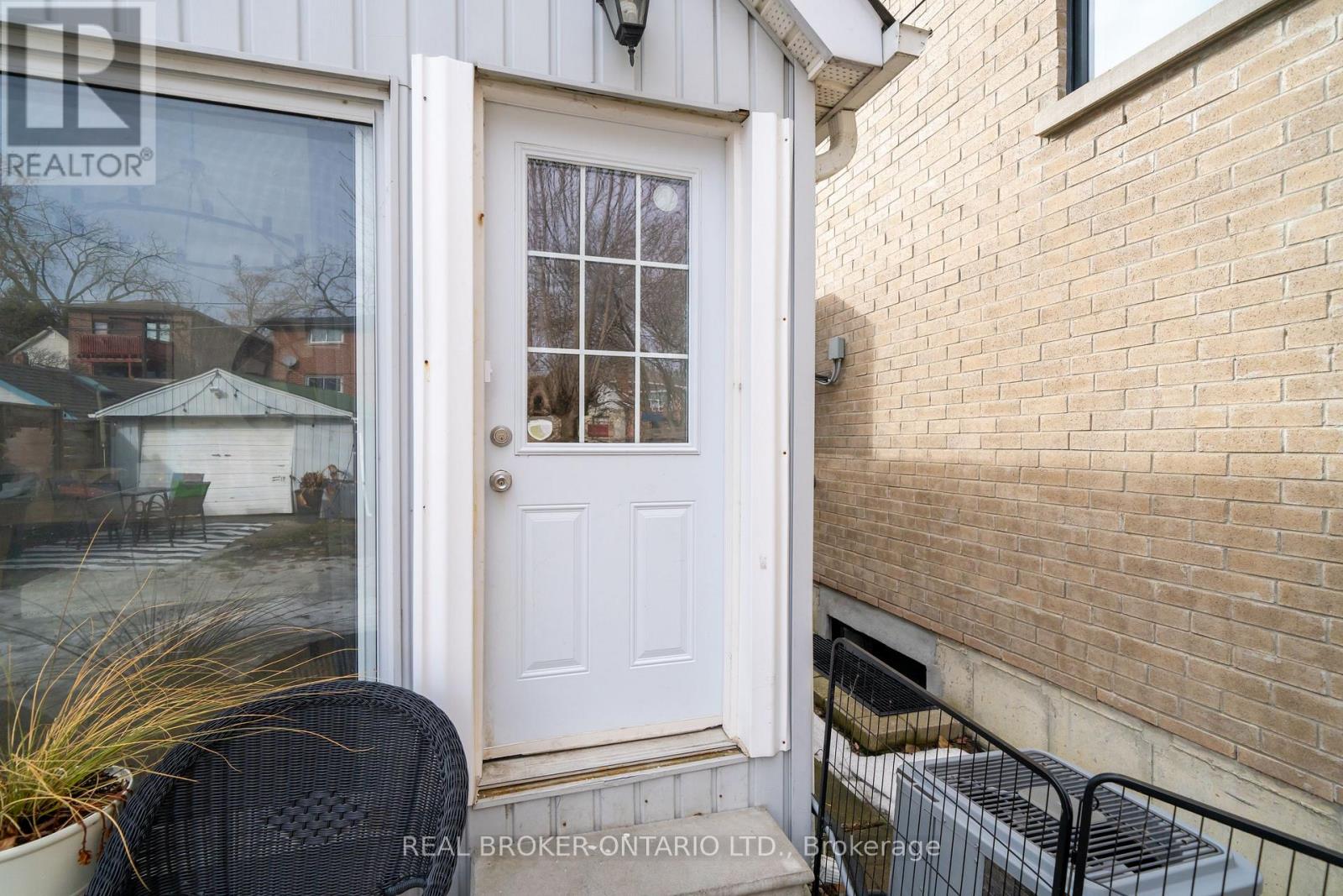 A white door with a glass window is on a brick wall.