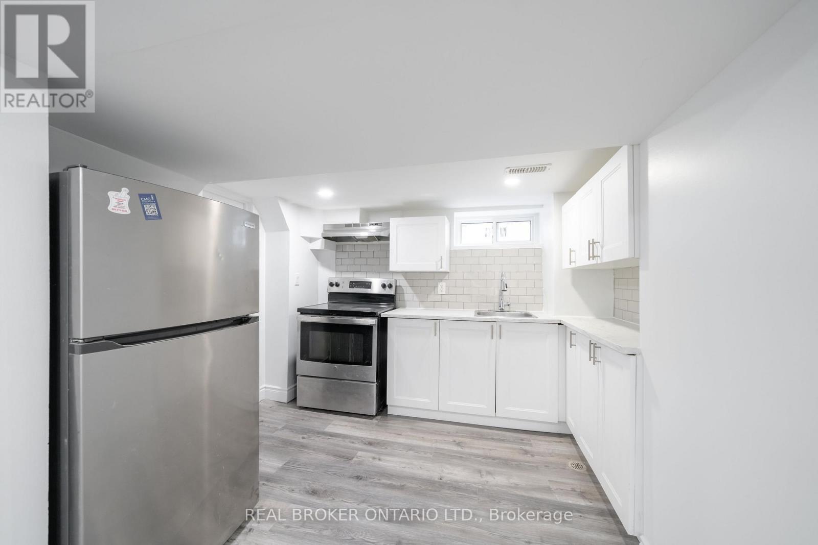 A modern kitchen with a stainless steel refrigerator and white cabinets.