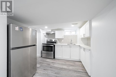 A modern kitchen with a stainless steel refrigerator and white cabinets.