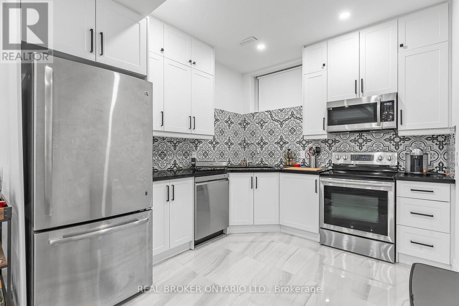 A kitchen with white cabinets and a stainless steel refrigerator.