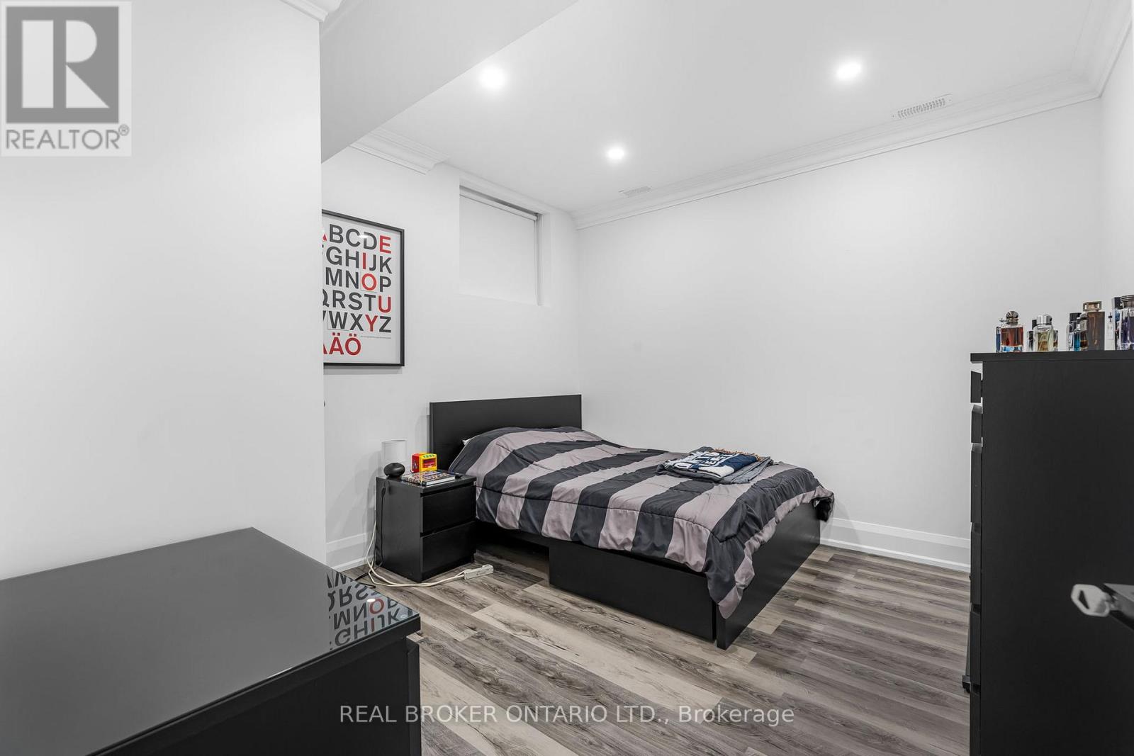 A bedroom with a bed, nightstand, and a framed poster on the wall.