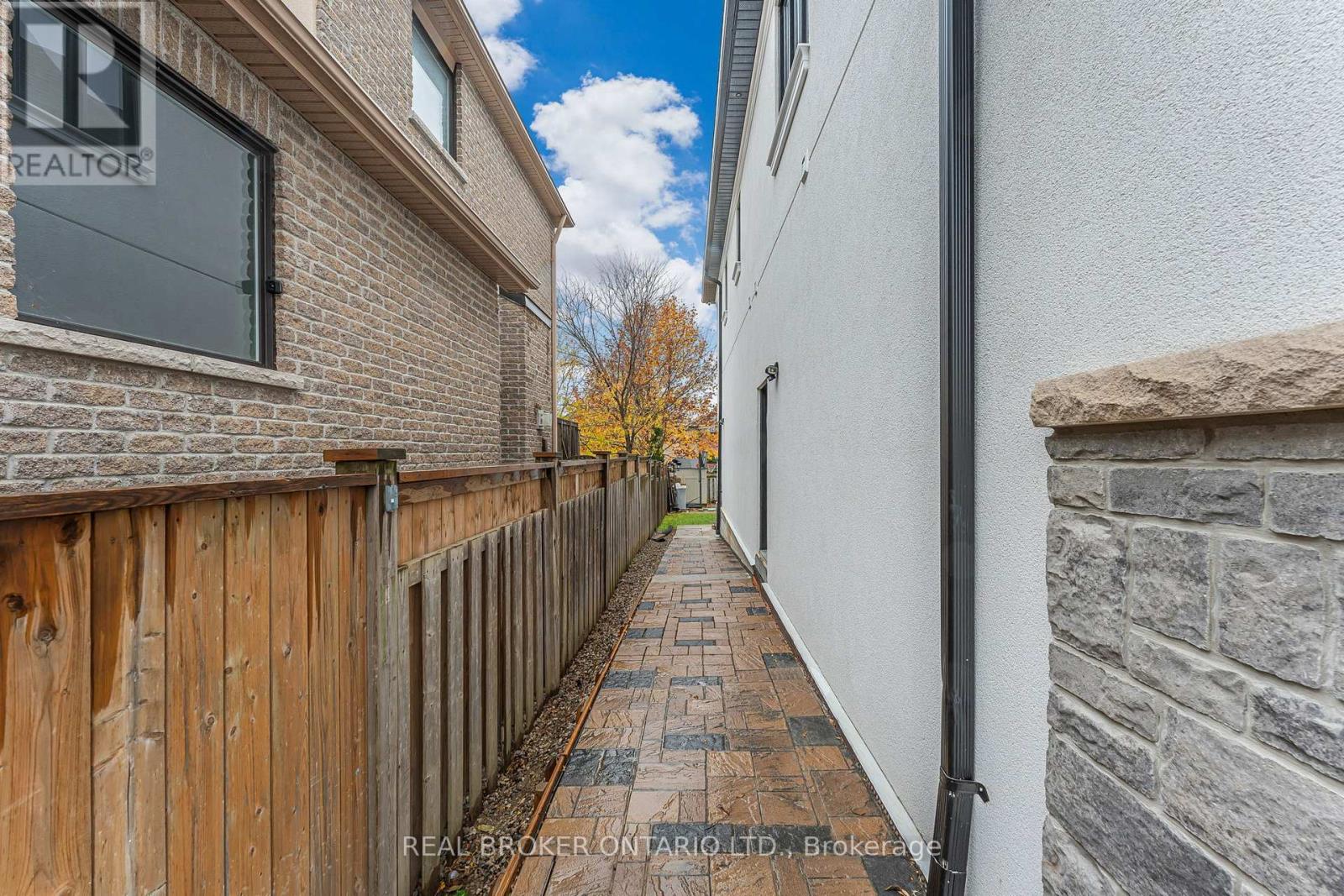 A narrow alley with a wooden fence on the left and a stone wall on the right.