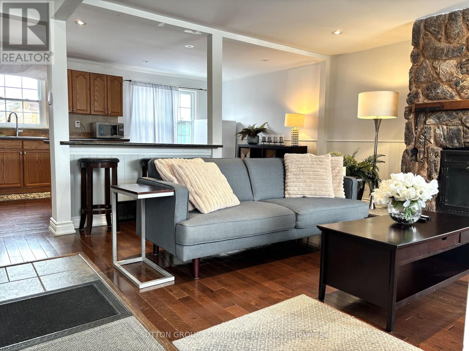 A living room with a grey couch and a stone fireplace.
