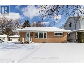 A house with a brown siding and a white roof is surrounded by snow.