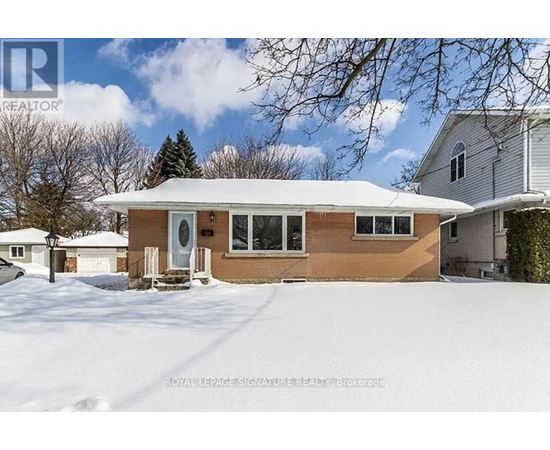 A house with a brown siding and a white roof is surrounded by snow.