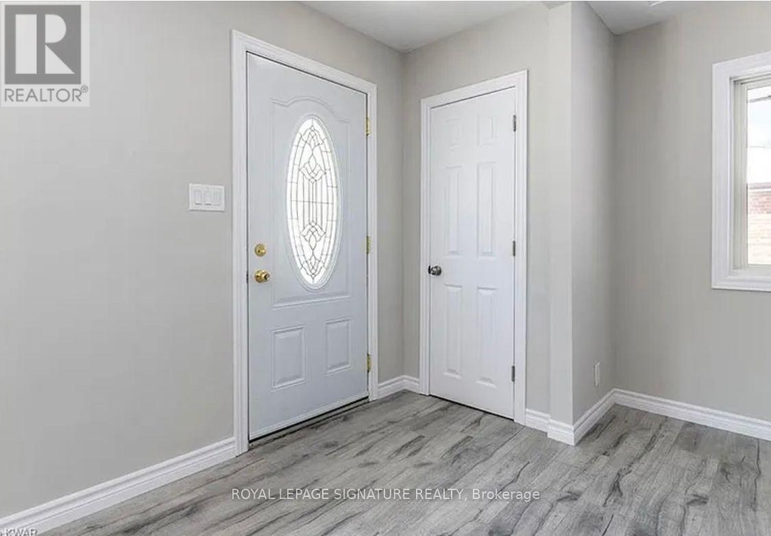 A white door with a glass window in the middle is in a room with a grey wall.