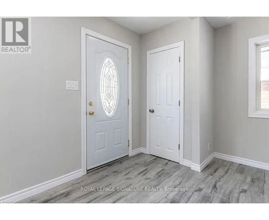 A white door with a glass window in the middle is in a room with a grey wall.