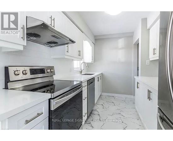 A modern kitchen with white cabinets and a black stove top oven.