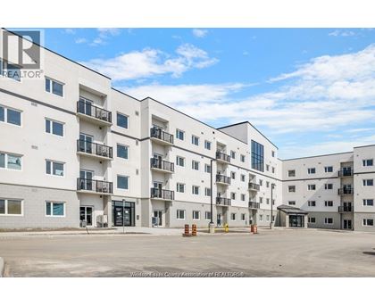 A large white apartment complex with multiple balconies and doors.
