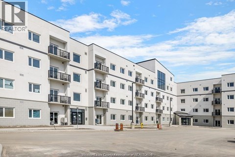 A large white apartment complex with multiple balconies and doors.